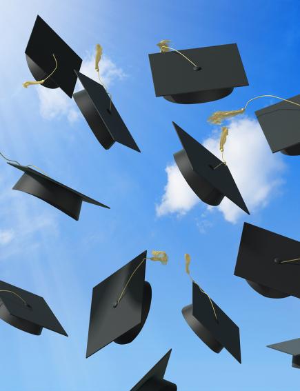 graduation caps being thrown up against a sky background